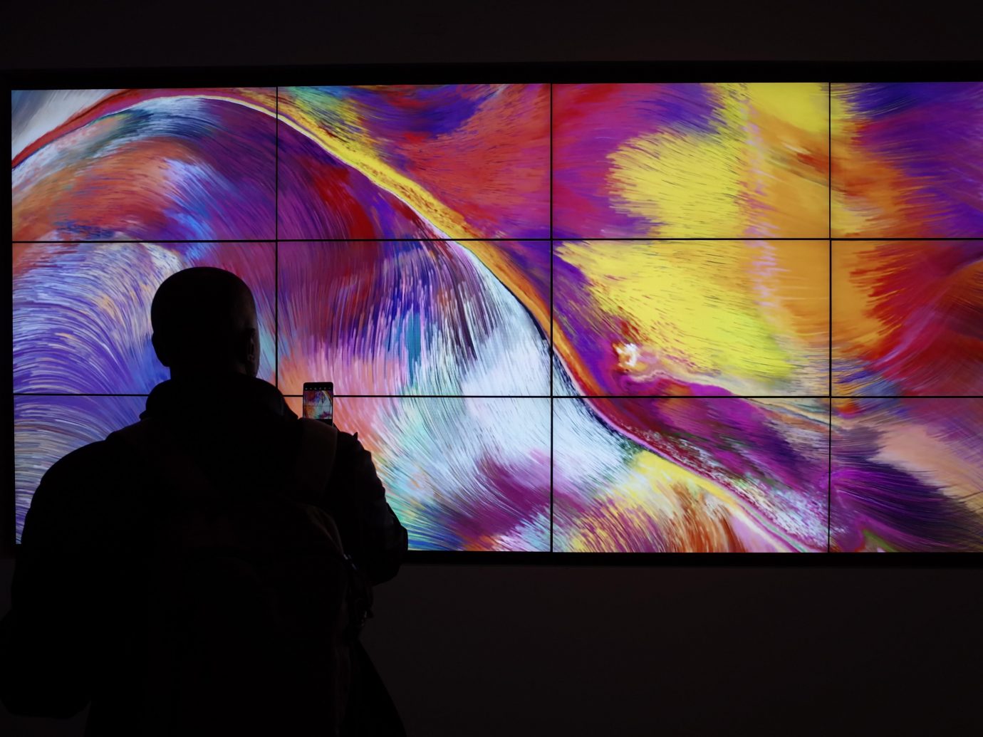 Modern, generative art installation displayed across multiple screens arranged side by side to form a single, large canvas.