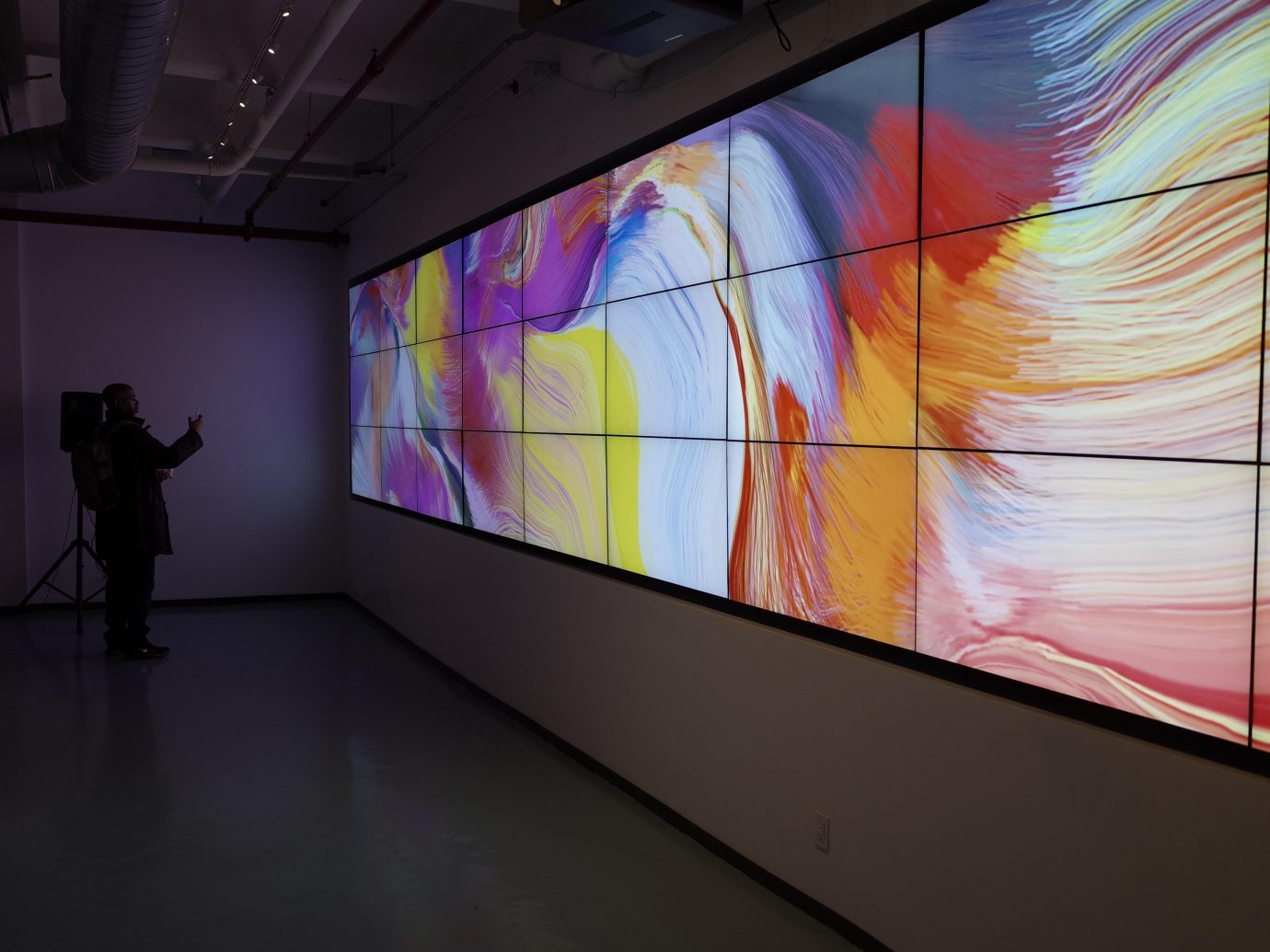 Modern, generative art installation displayed across multiple screens arranged side by side to form a single, large canvas.